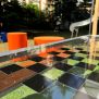 HPL Bench Chess and ludo game с шахматна дъска и оранжеви цилиндрични столове за външна употреба.